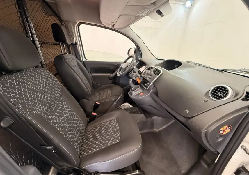 Vue intérieure côté conducteur du Renault Kangoo blanc 2016, montrant les sièges avant et la cloison tubulaire.