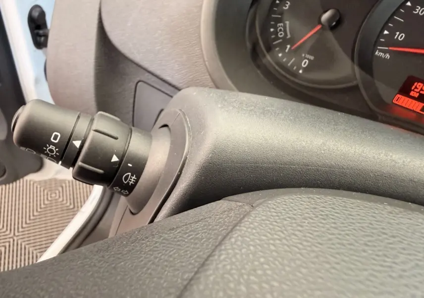 Gros plan sur la commande des phares et clignotants côté gauche du tableau de bord du Renault Kangoo blanc 2016.