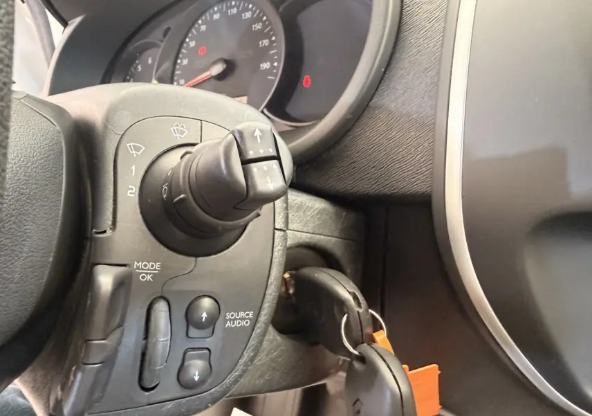 Gros plan sur le volant et le tableau de bord du Renault Kangoo 2016, avec commandes audio et clé insérée.
