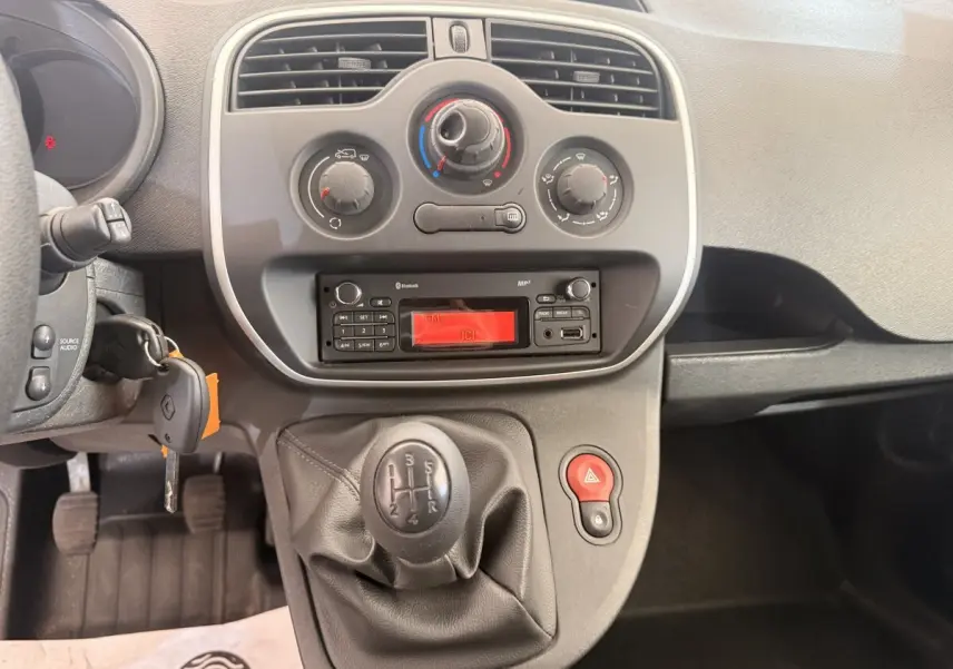 Vue intérieure centrée sur la console centrale et levier de vitesses manuelle du Renault Kangoo blanc de 2016.