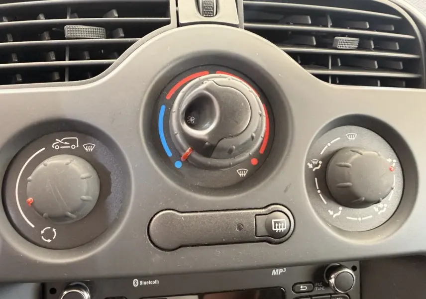 Gros plan sur les commandes de climatisation et radio Bluetooth du tableau de bord du Renault Kangoo blanc de 2016.