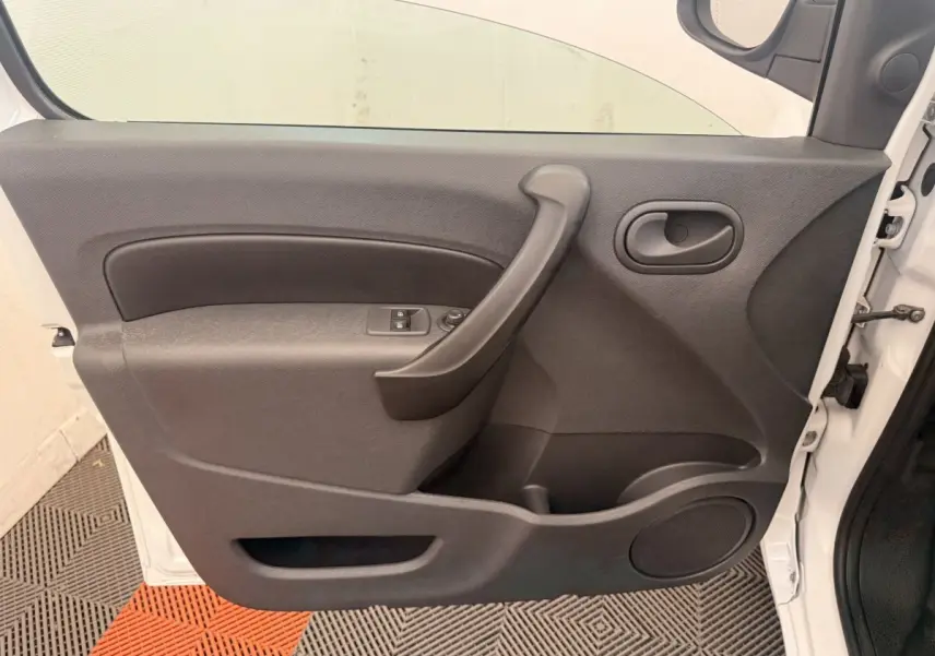 Vue intérieure de la porte avant gauche du Renault Kangoo blanc, avec poignée et commandes de vitres électriques.