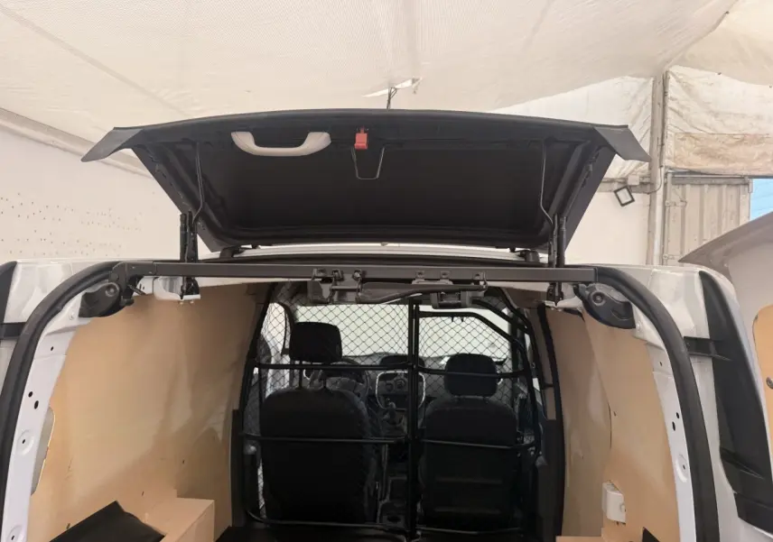 Vue arrière du Renault Kangoo blanc 2016 avec porte ouverte et cloison tubulaire pleine visible à l'intérieur.