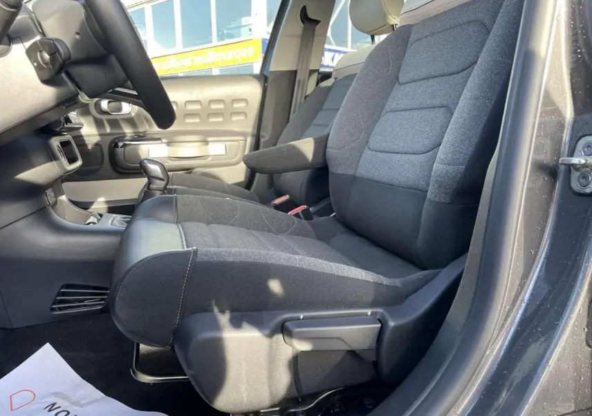 Intérieur côté conducteur de la Citroën C3 1.2 Shine 2021 gris foncé, sièges tissu et cuir avec levier de vitesse manuel visible.