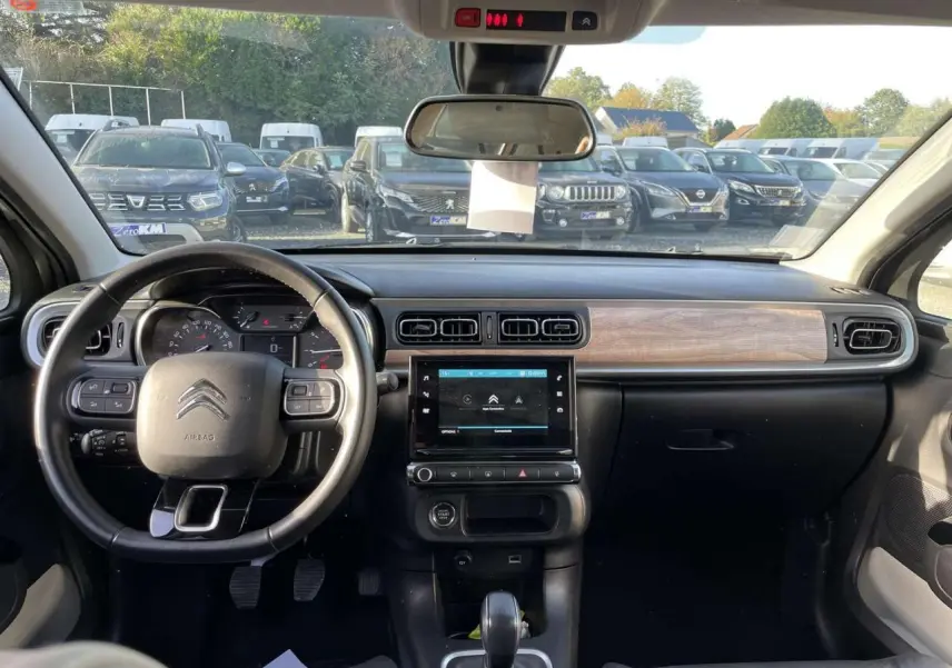 Intérieur de la Citroën C3 1.2 83 Shine 2021, tableau de bord noir avec insert bois et écran tactile central visible.