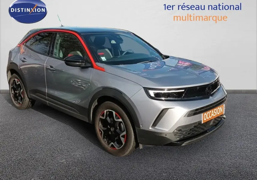 Opel Mokka GS Line gris quartz en 3/4 avant droit avec jantes noires et touches rouges distinctives.