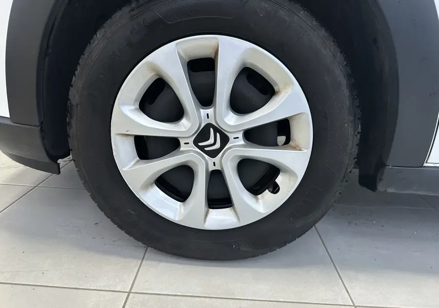 Gros plan sur la roue avant droite d'une Citroën C3 blanche de 2018 avec jante en alliage et logo Citroën central.