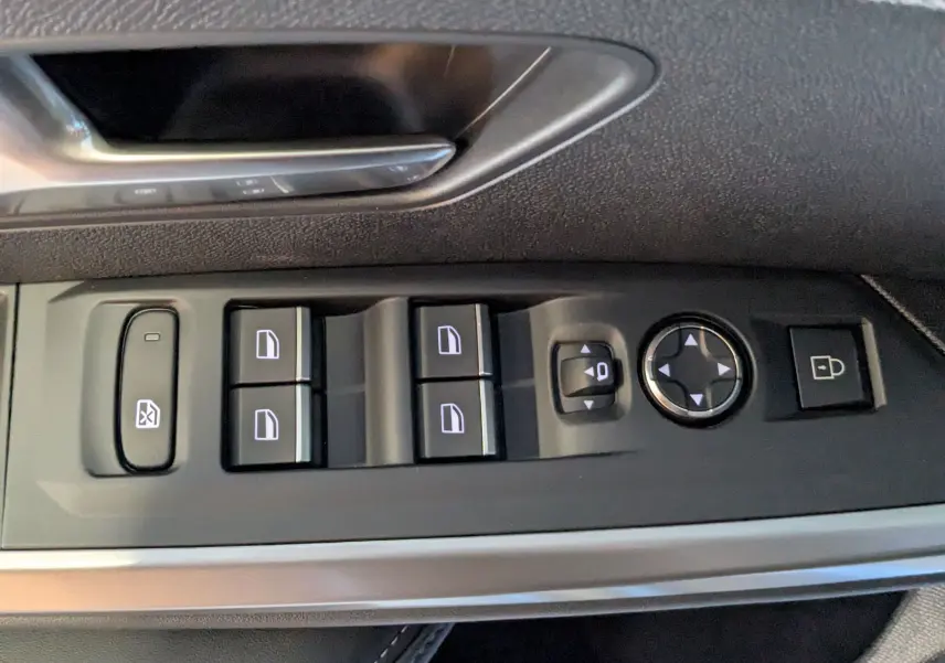 Gros plan sur les commandes de lève-vitres et rétroviseurs côté conducteur du Peugeot 3008 blanc Okenite.