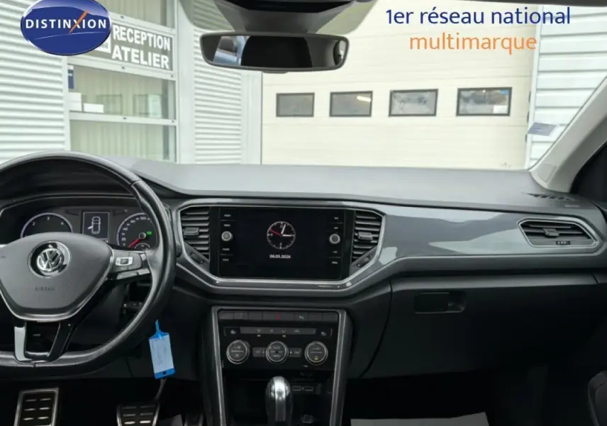 Vue intérieure du tableau de bord noir du Volkswagen T-Roc 2020 avec volant multifonctions et écran central tactile.