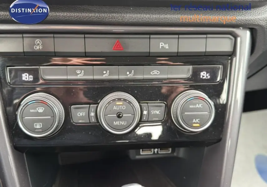 Vue rapprochée du tableau de bord du Volkswagen T-Roc noir, mettant en valeur la climatisation automatique et les commandes centrales.