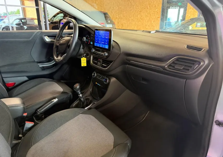 Vue intérieure côté conducteur du Ford Puma gris 2021, avec tableau de bord noir et écran tactile central allumé.