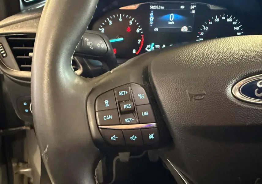 Gros plan sur le volant noir et le tableau de bord digital du Ford Puma gris 2021, avec commandes au volant visibles.