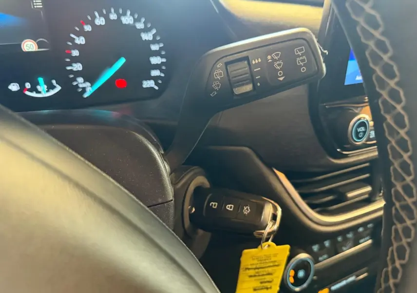 Détail intérieur du tableau de bord côté gauche d’un Ford Puma gris 2021, avec clé insérée et commandes au volant visibles.