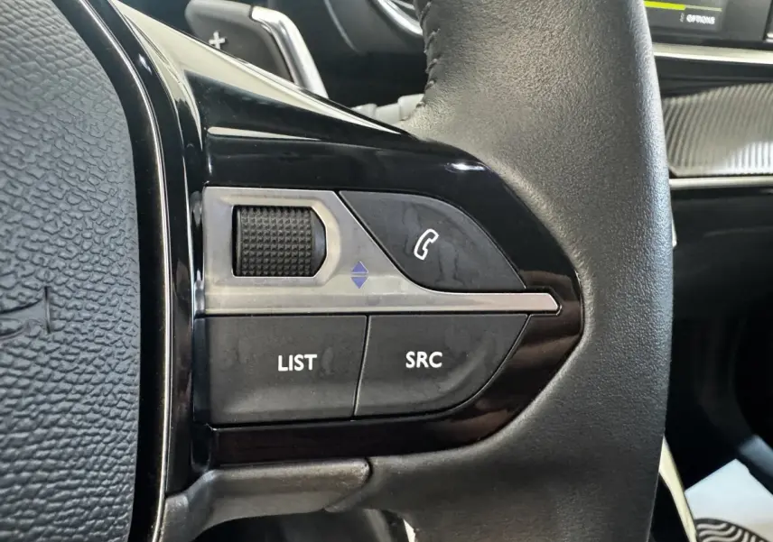 Gros plan sur les commandes gauche du volant cuir noir du Peugeot 2008 2022, boutons LIST, SRC et téléphone.