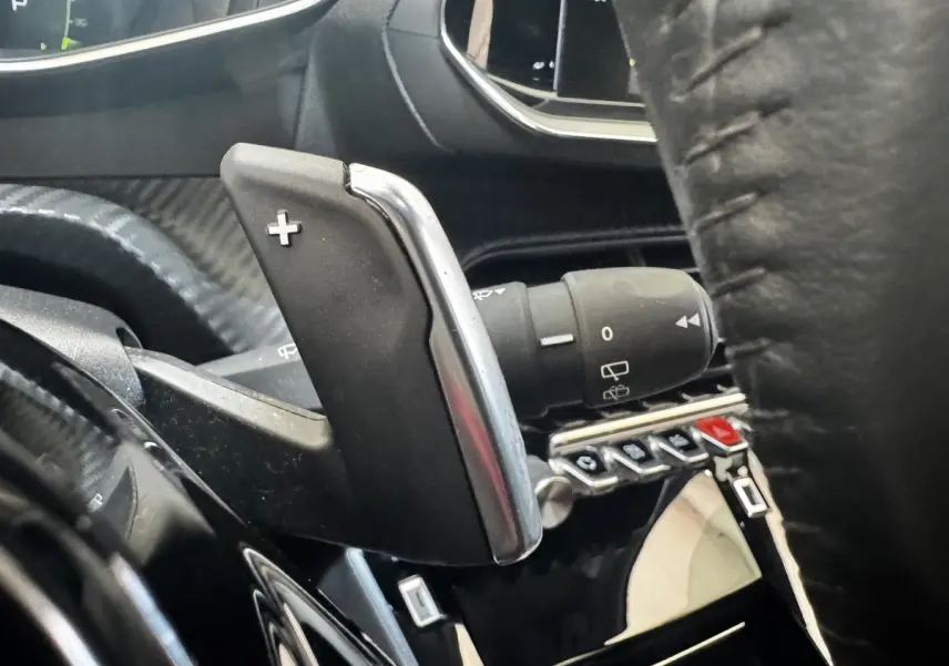 Gros plan sur la palette de changement de vitesse droite en plastique noir et chrome dans l’habitacle noir du Peugeot 2008.