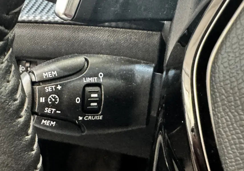 Gros plan sur la commande de régulateur de vitesse au volant cuir noir du Peugeot 2008 BlueHDi 130 2022.