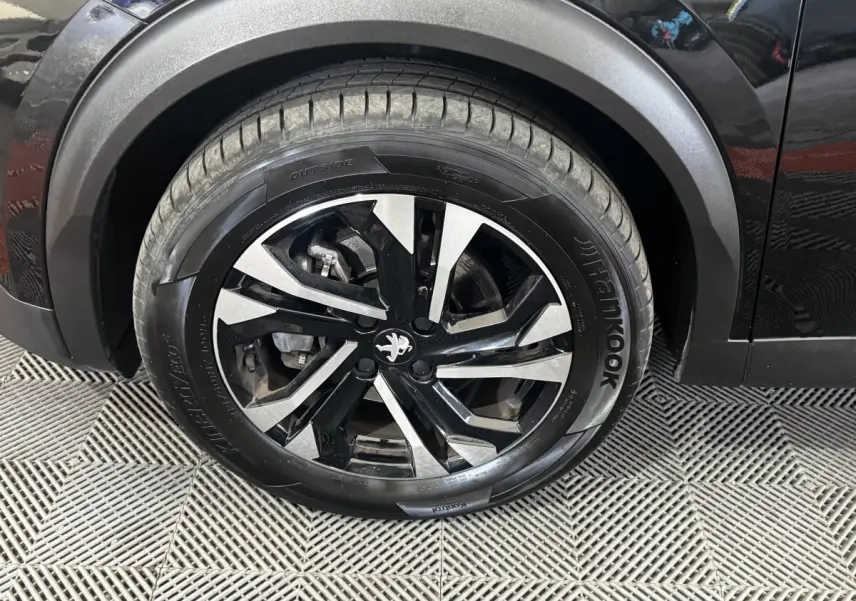 Gros plan sur la roue avant droite noire avec jante alliage bicolore du Peugeot 2008 noir 2022.