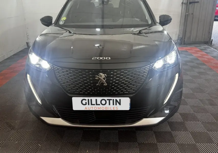 Vue frontale d’un Peugeot 2008 noir avec phares LED allumés et calandre distinctive en intérieur showroom.