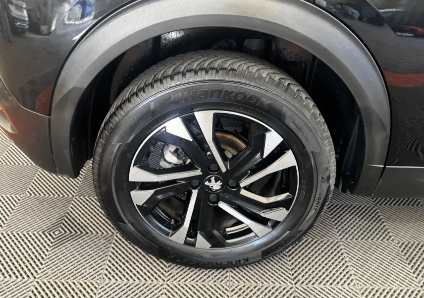 Gros plan sur la roue avant droite noire avec jante alliage bicolore du Peugeot 2008 noir 2022.