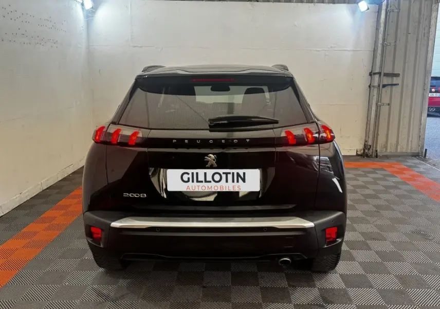 Vue arrière d’un Peugeot 2008 noir 2022 avec feux arrière LED et logo Peugeot visible sur un sol à damiers gris et orange.