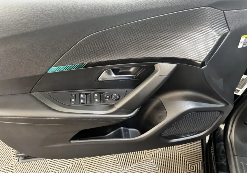 Vue rapprochée de la porte avant gauche noire du Peugeot 2008 2022 avec insert décoratif carbone et commandes électriques.