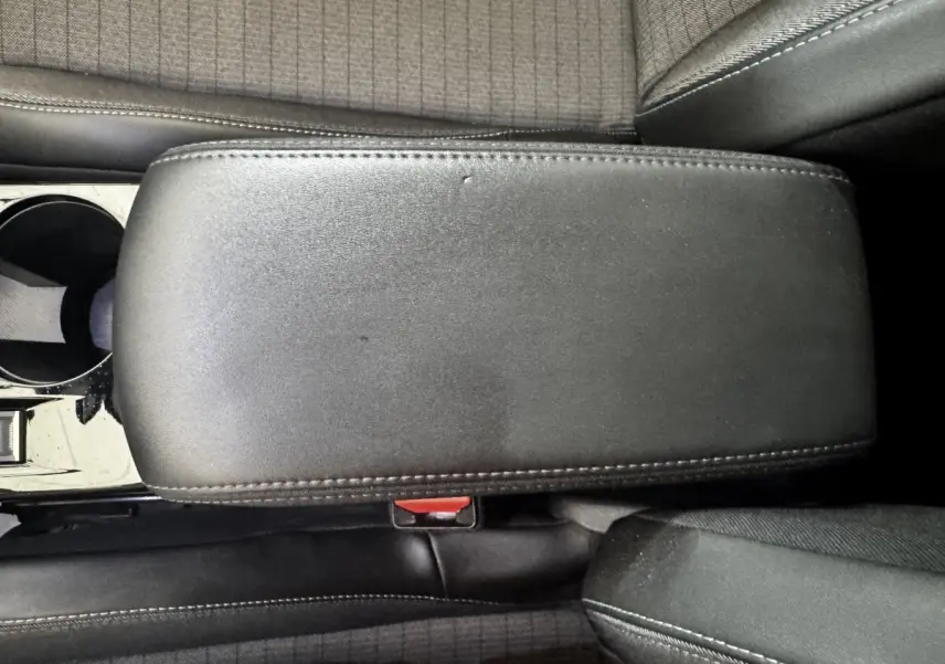 Vue rapprochée de l'accoudoir central en cuir noir et des sièges tissu gris foncé à motifs du Peugeot 2008 noir.