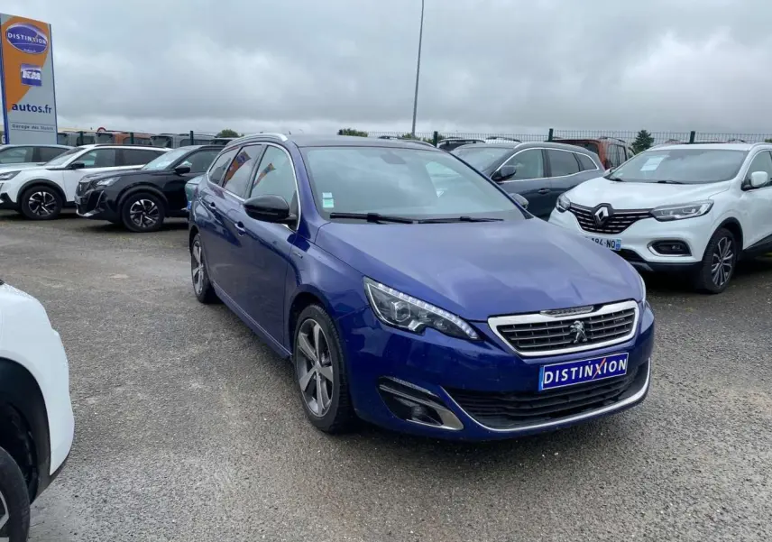 Peugeot 308 SW bleu magnétique vue 3/4 avant gauche sur parking avec calandre chromée et jantes alliage.