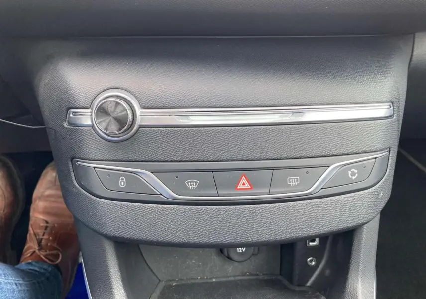 Vue rapprochée de la console centrale noire de la Peugeot 308 SW GT Line 2017 avec commandes de climatisation et bouton hazard.