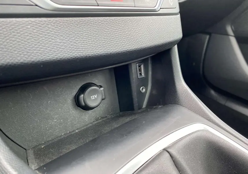 Gros plan sur la prise 12V et port USB dans la console centrale noire d'une Peugeot 308 SW 2017.