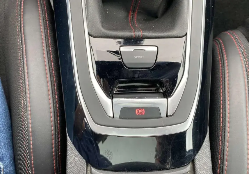 Gros plan sur la console centrale de la Peugeot 308 SW GT Line avec surpiqûres rouges et bouton mode sport.