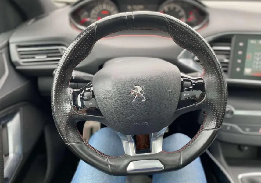 Volant cuir noir à surpiqûres rouges de la Peugeot 308 SW GT Line 2017, vue centrée sur le poste de conduite.