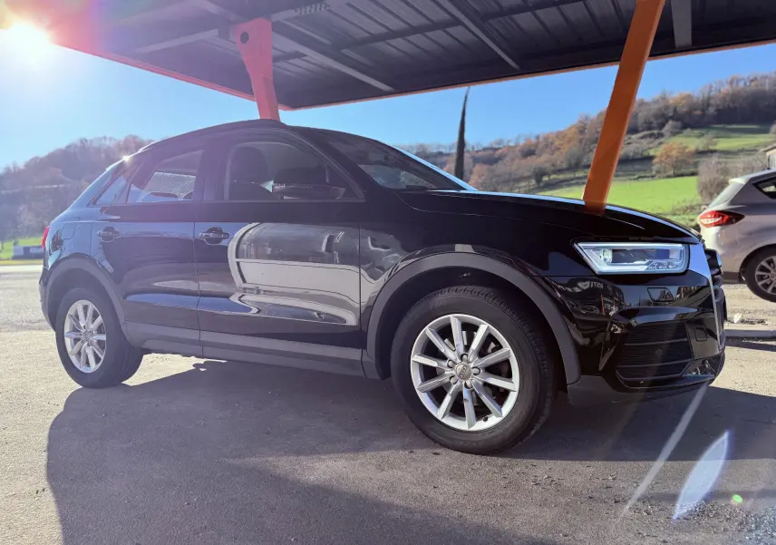 Audi Q3 noir en vue de profil côté gauche sous un abri, avec jantes alliage et phares LED visibles.