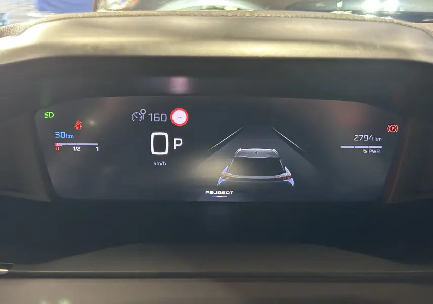 Affichage numérique du tableau de bord de la Peugeot 2008 bleu Obsession, montrant la vitesse et l'assistance à la conduite.