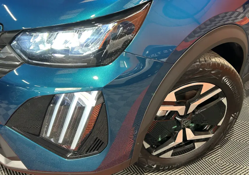 Gros plan sur l'avant droit bleu Obsession du Peugeot 2008 II Ph.2 avec phares LED allumés et jante alliage distinctive.