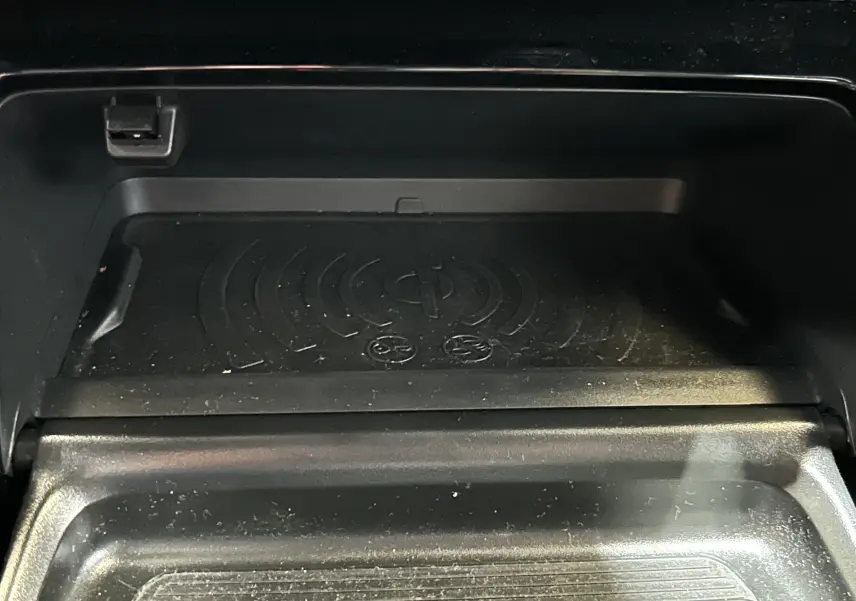 Gros plan sur le chargeur sans fil intégré dans le compartiment central du Peugeot 2008 Bleu Obsession 2025.