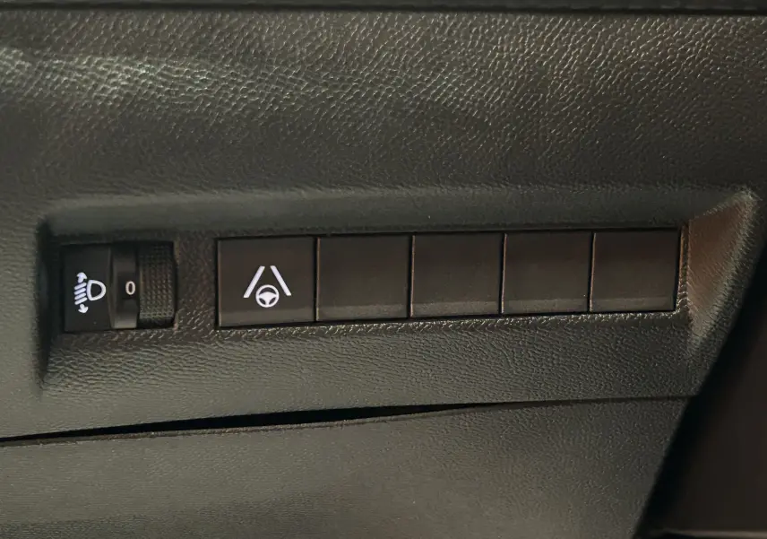 Gros plan sur les commandes de réglage des phares et d’aide au maintien de voie dans un Peugeot 2008 Bleu Obsession.