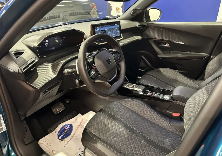 Vue intérieure côté conducteur du Peugeot 2008 Bleu Obsession 2025, avec tableau de bord numérique et écran central tactile.