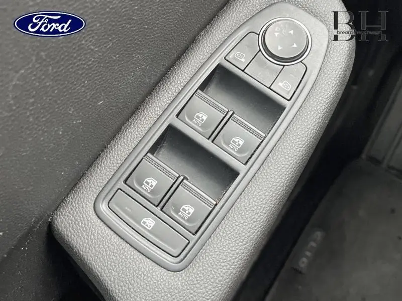 Gros plan sur la commande des vitres électriques côté conducteur, plastique noir texturé avec boutons auto.