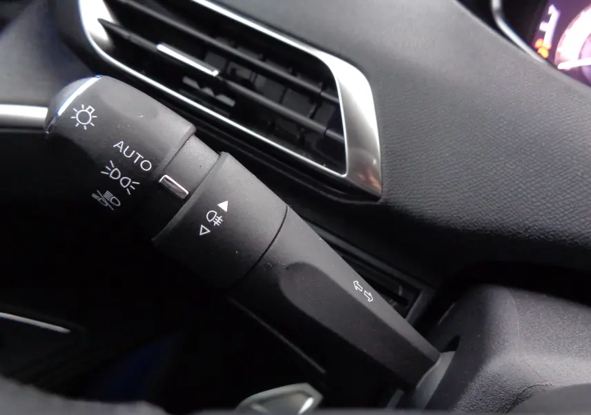 Gros plan sur la commande des phares et clignotants du Peugeot 5008 gris platinium métal, intérieur noir.