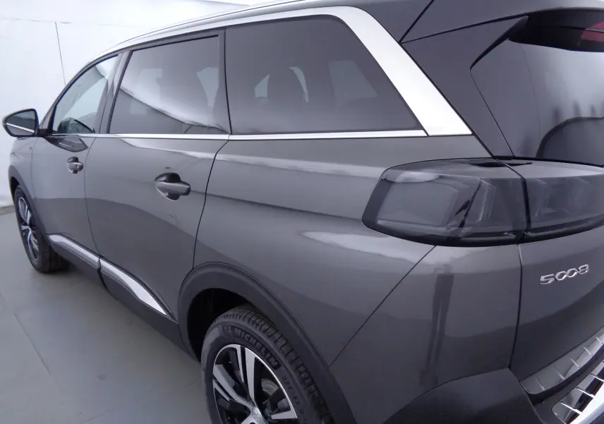 Vue 3/4 arrière côté gauche du Peugeot 5008 gris platinium métal avec feux arrière fumés et jantes alliage.