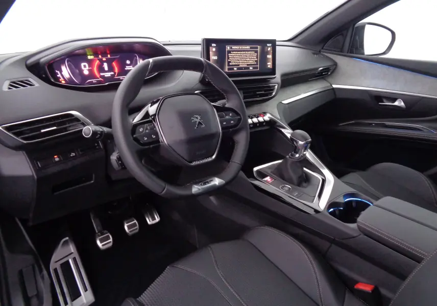 Intérieur avant droit du Peugeot 5008 gris platinium 2023, volant compact, écran tactile et levier de vitesse manuel visibles.