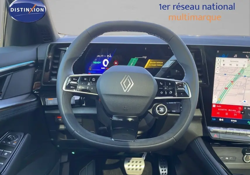 Vue intérieure centrée sur le volant Renault Espace blanc nacré 2025 avec tableau de bord numérique et écran tactile GPS.