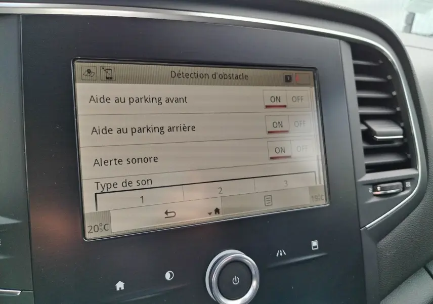 Écran tactile central de la Renault Mégane IV Business noir, affichant les réglages d'aide au parking et alertes sonores.