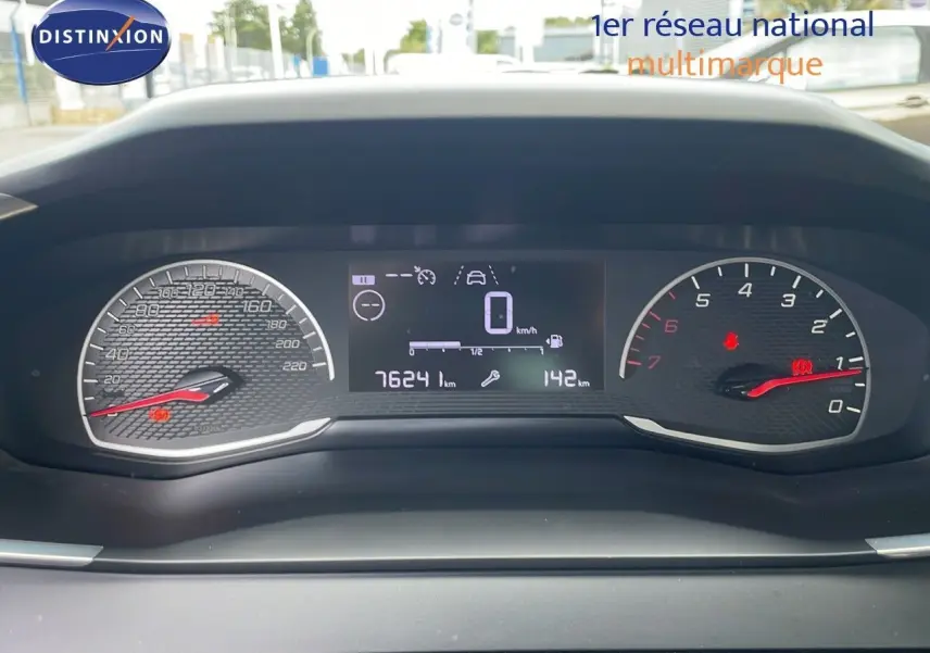 Tableau de bord numérique de Peugeot 208 blanc banquise, affichant 76241 km et vitesse à zéro, vue frontale rapprochée.