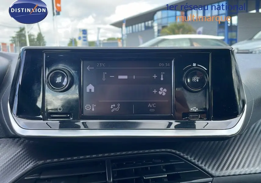 Écran tactile de climatisation et commandes dans l'habitacle d'une Peugeot 208 blanc banquise, vue de face.