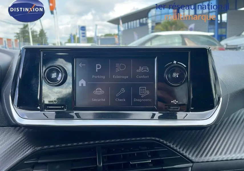 Écran tactile central du tableau de bord de la Peugeot 208 blanc banquise, avec commandes de confort et sécurité affichées.