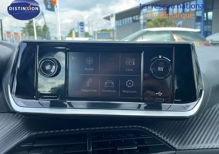 Tableau de bord du Peugeot 208 blanc banquise 2021, écran tactile central avec commandes climatisation et multimédia visibles.