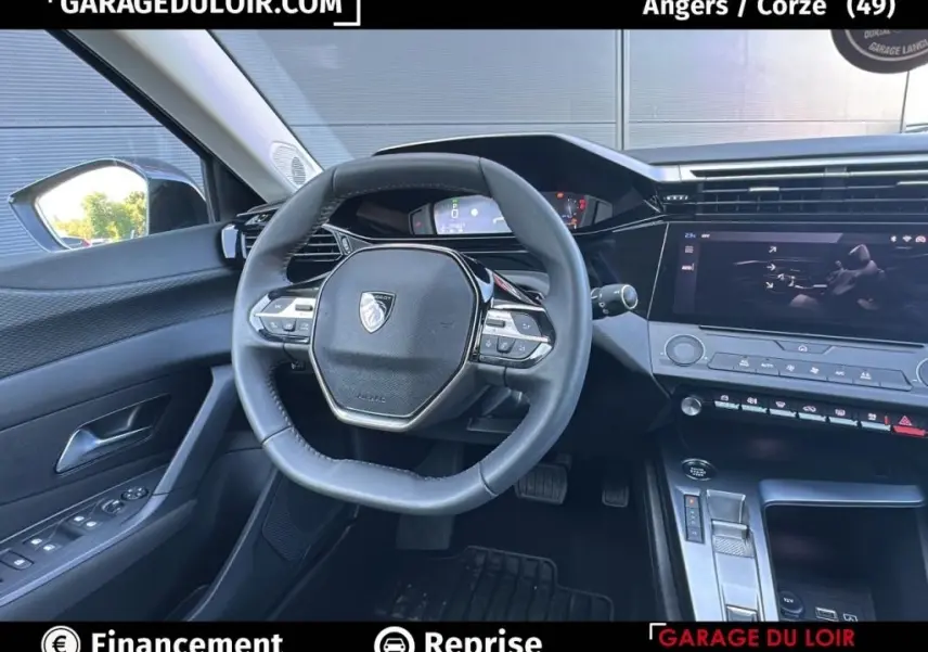 Vue intérieure du poste de conduite de la Peugeot 308 gris clair, avec volant cuir multifonctions et écran tactile central.