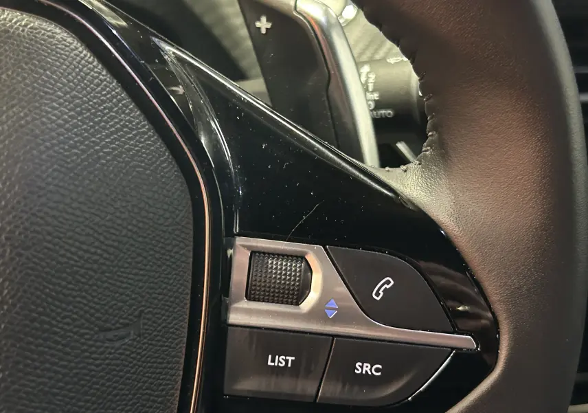 Gros plan sur le volant en cuir noir du Peugeot 2008 II Ph.2 Allure Hybrid 145, soulignant sa finition élégante.