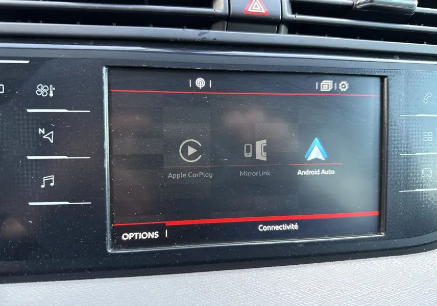 Écran tactile central du tableau de bord d'une Citroën C4 Picasso gris, affichant les options Apple CarPlay, MirrorLink et Android Auto.